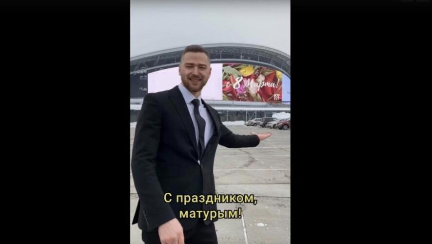 Сначала певец играет на укулеле на смотровой площадке с видом на Дворец земледельцев