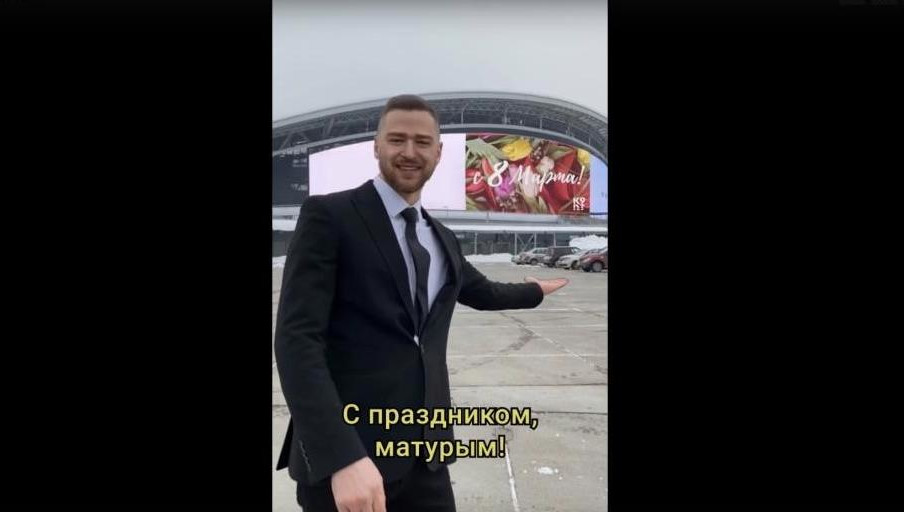 Сначала певец играет на укулеле на смотровой площадке с видом на Дворец земледельцев