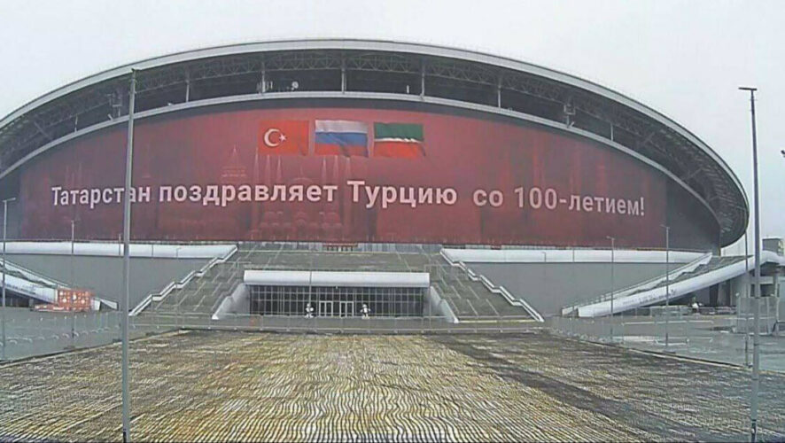На красном фоне изображены три флага: России