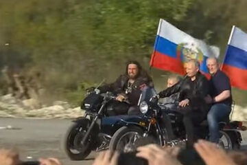 Президент ехал за рулем «Урала» с российским флагом.
