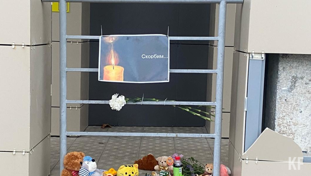 Люди несут к месту гибели ребёнка игрушки и цветы.