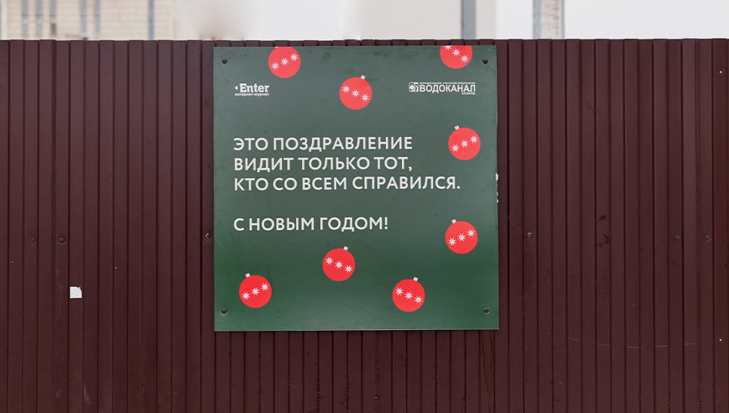 Печатные постеры приклеили на коричневые заборы