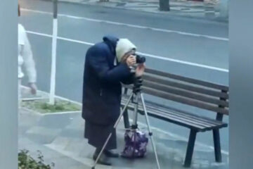 На видео пенсионерка фотографирует улицу.