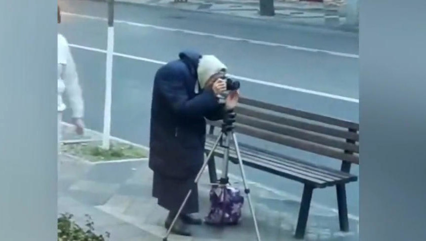 На видео пенсионерка фотографирует улицу.