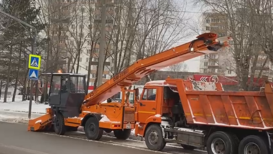 Спецтехника убирает снег с обочин и закидывает в &laquo;КамАЗ&raquo;.