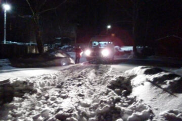 Машина женщины застряла в снежном заносе ранним утром.